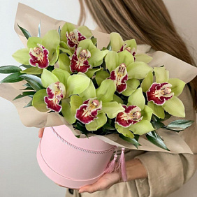 9 орхидей с зеленью в  шляпной коробке